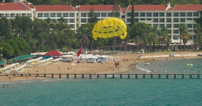 Parachuting In Turkey. Yellow Parasail Wing Pulled By Boat. Sea Summer Recreation. Parasailing With Boat Over Sea In Alanya In Beautiful Summer Day. Holiday Fun Activities. Tropical Paradise.