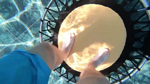 Aqua Jump man legs jumping on a trampoline in the water, water gymnastics close-up.
