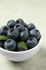 Bowl of fresh tasty blueberries on light grey table, closeup