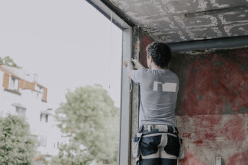 Caucasian male builder clean the window opening.