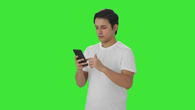Indian man scrolling through phone Green screen