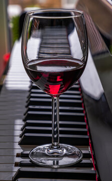 Glass of red wine on piano keyboard. Music and wine concept, Space for text, Selective focus.