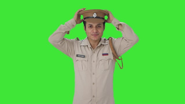 Happy Indian police officer wearing hat and getting ready Green screen