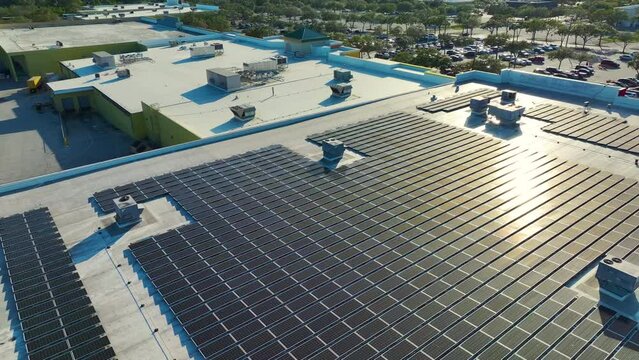 Aerial view of blue photovoltaic solar panels mounted on shopping mall building roof for producing green ecological electricity. Production of sustainable energy concept