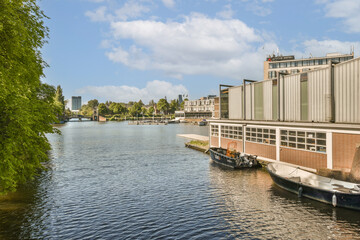 Obraz premium some boats in the water and buildings on the other side of the river, with blue skies overhead above them
