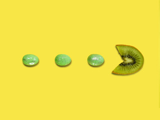 Creative layout made of kiwi fruit eating green Easter eggs against yellow background. Original lemon decoration. Fruit concept. Minimal summer design. Creative Easter idea.
