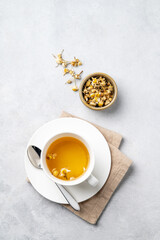 Chamomile herbal tea in a white cup on a light background with dry flowers. The concept of a healthy detox drink for health and sleep.