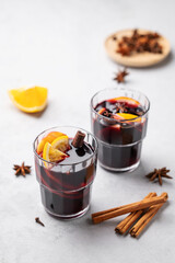 Mulled wine with orange, apple  and cinnamon in glasses on a light background. The concept of a traditional winter hot drink