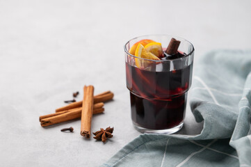 Mulled wine with orange, apple  and cinnamon in glass on a light background. The concept of a traditional winter hot drink with spices and fruits.
