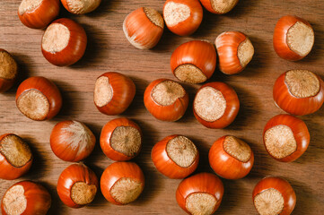 Hazelnuts scattered on a wooden background.