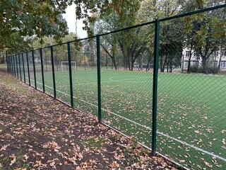 An empty football field is covered with yellow autumn leaves