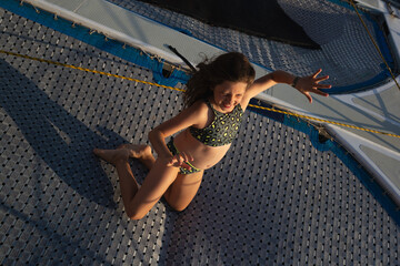 cute teen girl having fun on a yacht in the open sea - obrazy, fototapety, plakaty