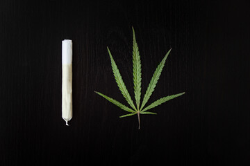 Preparing a cannabis joint with tobacco and rolling paper with marijuana bud on black background....