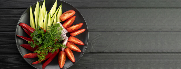 Platter of assorted fresh vegetables on black background. Banner.