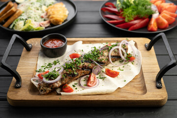 Lula kebab with vegetables and pita bread on a wooden board at restaurant. Arabic cuisine