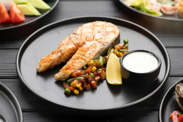 Grilled salmon fish steak with vegetables on black plate. Keto diet concept.