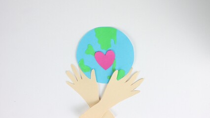Green globe planet eco concept. Earth day postcard close up. Stop motion paper animation. Pink heart beating. Ecology concept. Hands hold love sign. People show hug gesture. Whole world art card.