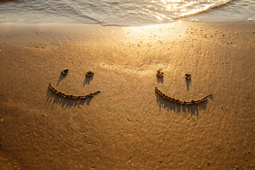 two emoticon happy smile face painted on jetted beach sand by sea