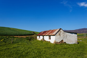A beautiful landscape with a dilapidated old house and green fields near Caledon, Western Cape, South Africa.
