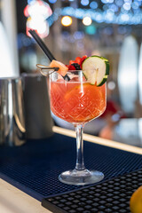 fresh orange cocktail decorated with cucumber and fruits on a bar counter.