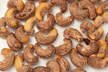 Burned cashews nut with peel on white background.