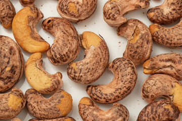 Burned cashews nut with peel on white background.