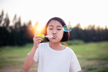 Portrait of funny lovely little girl blowing soap bubbles