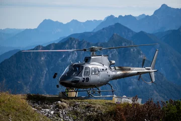 Outdoor kussens Gray cargo helicopter lands on ridge of a mountain in the Alps in autumn © A2LE