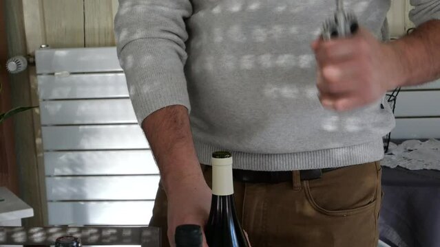 Homme d&eacute;bouchant une bouteille de vin rouge avec un tire-bouchon
