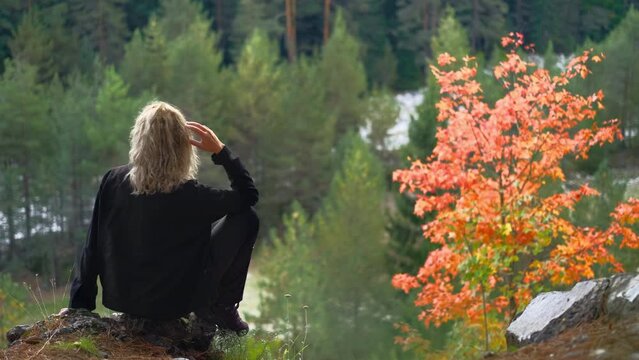 Silhouette of a woman on the edge of cliff admiring the colors of autumn forest, weekend hikes in the forest, 4K footage in real time. Idea for a background or film about the changing of the seasons