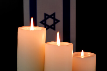 Israel flag and burning candles on black background. Memorial and pray concept. 