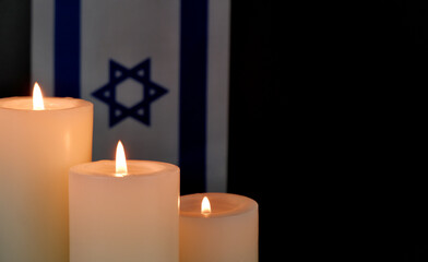 Israel flag and burning candles on black background. Memorial and pray concept. Copy space for text.