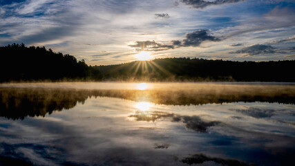 Dramatic sunrise over a lake with mist and reflections