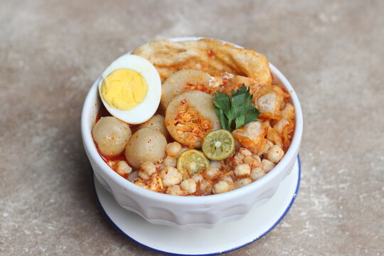 Meatball chicken soup with egg and lime topping in white bowl