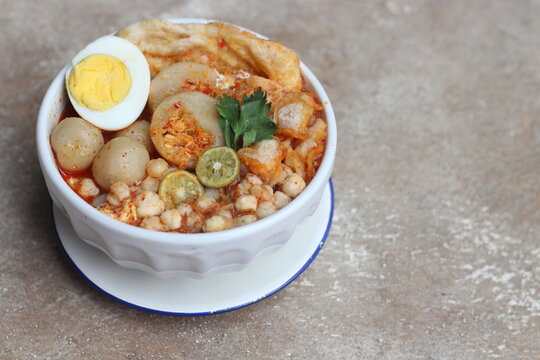 Meatball chicken soup or baso aci with egg and lime topping in white bowl from Bandung , West Java Indonesia.
