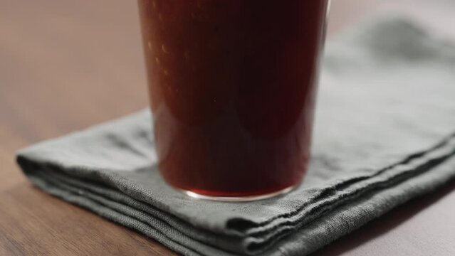Slow motion making nitro coffee in thin glass on walnut table