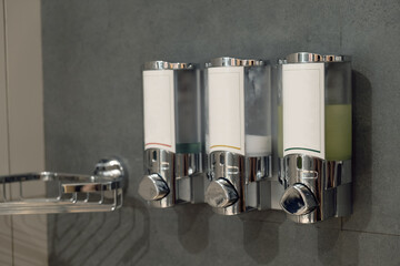 Three dispensers for cosmetics in the bathroom of a hotel room. Interior details of a chain hotel. Taking care of hotel guests.