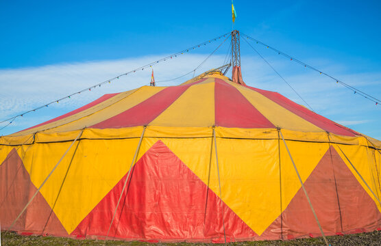 Colourful circus tent against a blue sky. Red-yellow awning of a moving circus