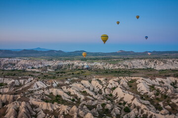 Hot air balloons flying over bizarre rock landscape in Cappadoci