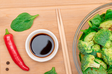 Fresh Green Salad of Avocado, Broccoli, Spinach and Cucumber with Soy Sauce and Red Hot Pepper on Wooden Cutting Board. Vegan Salad. Vegetarian Culture. Raw Food. Healthy Eating and Vegetable Diet