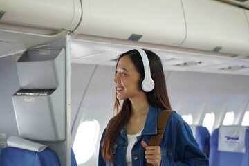 Asian woman sitting on airplane playing with cell phone and looking out window on vacation travel concept Talk about business on airplanes, listen to music, watch movies, relax, travel.