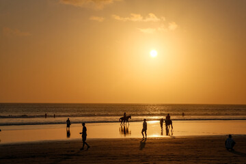 A Beach Abuzz with Life, Bathed in the Glow of Kuta's Orange Twilight