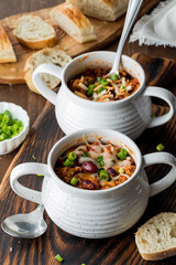 Homemade chili con carne in soup crocks, served with a crusty baguette.