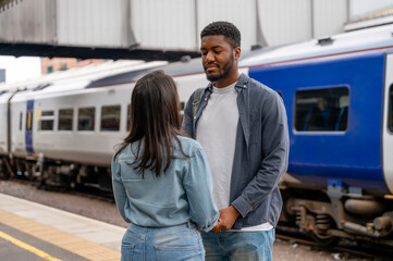 Happy young couple awaiting train at railway station platform