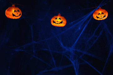 Halloween. Garland with orange pumpkins on the background of cobwebs