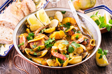 Traditional Portuguese seafood cataplana with king prawns, vongole clam and squid in white wine...