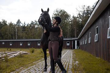 Equestrian sports. A young woman, a rider and her horse, going out for training near the stable