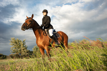 Horsewoman in equestrian sports gear, riding a horse, against an expressive sky, horseback riding...