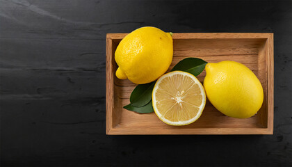 Lemons in a wooden tray on a black background 