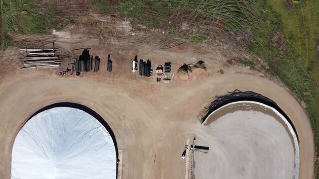 Drone view over two grain storage piles being filled and covered
